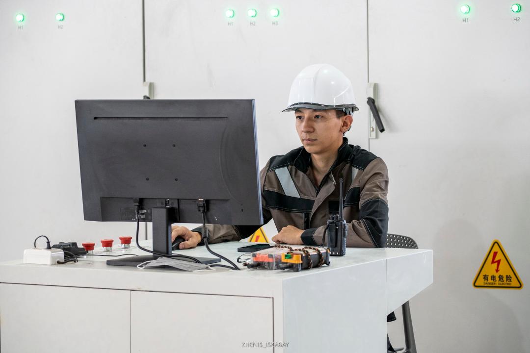 Зауыт жұмысшылары компьютер алдында