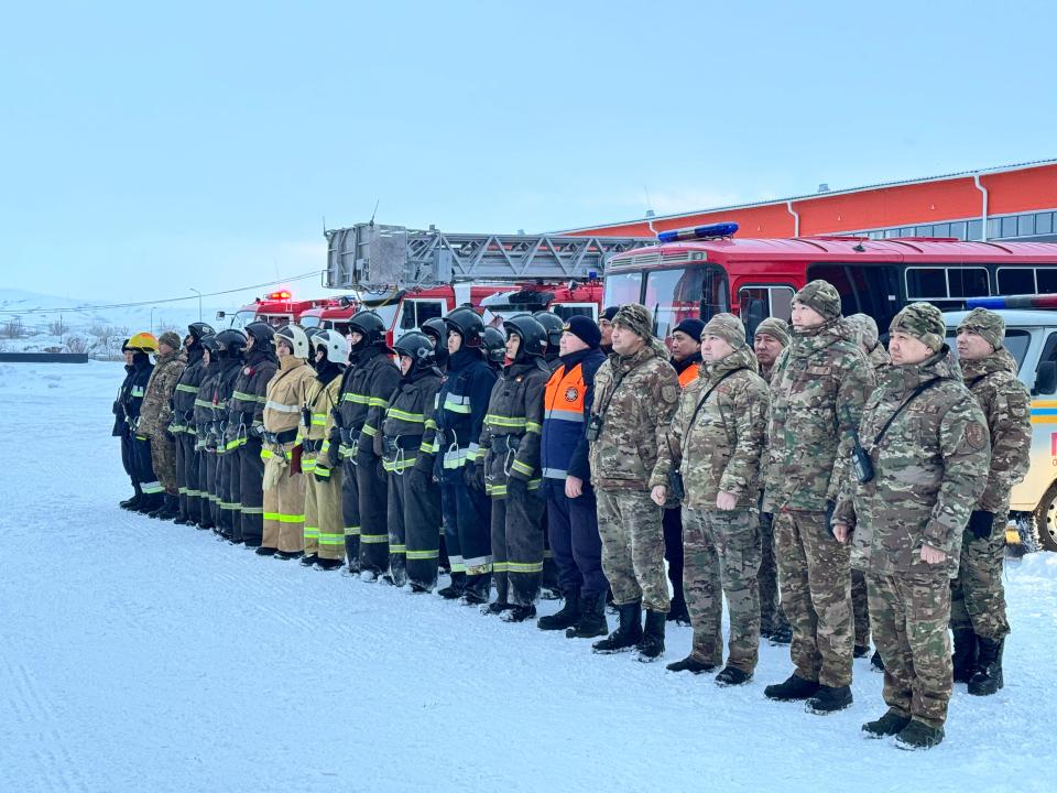 Қарда тұрған өрт сөндірушілер мен әскери қызметшілердің тобы.