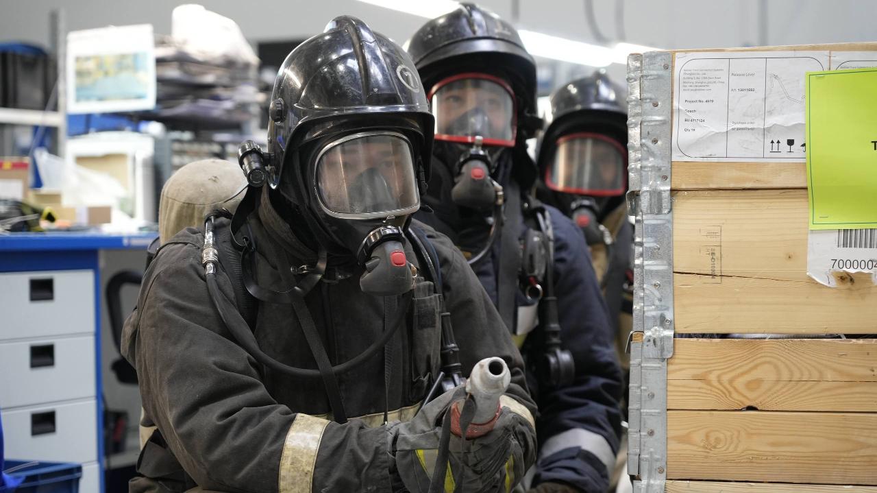 Қорғаныш костюмі мен маска киген жұмысшы дәнекерлеуге дайындалып тұр.